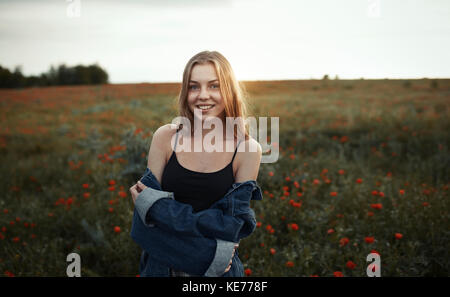 Portrait lächelnde junge Frau im ländlichen Bereich mit Wildblumen Stockfoto