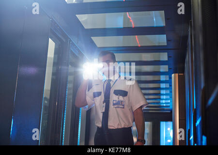 Männlicher Wachmann mit Taschenlampe im Serverraum Stockfoto