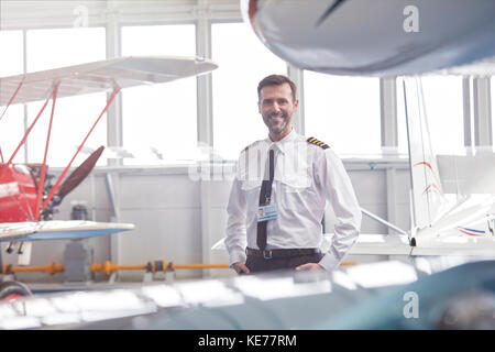 Porträt Lächeln männlich Pilot in der Nähe von Flugzeug im Hangar Stockfoto