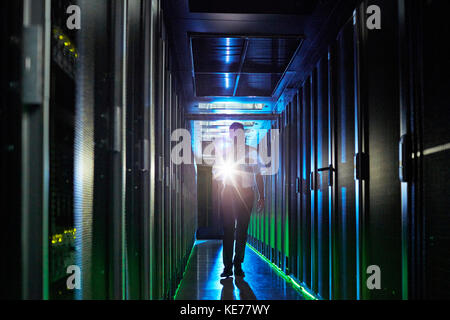 Männlicher Wachmann mit Taschenlampe, der im dunklen Serverraum läuft Stockfoto
