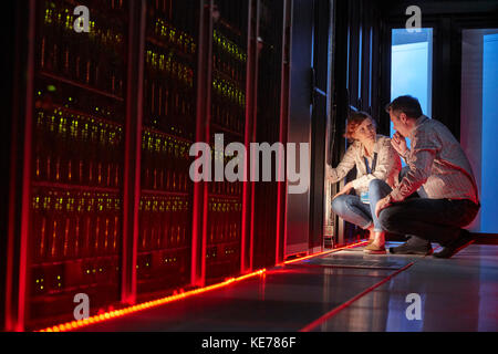 IT-Techniker sprechen bei leuchtendem Panel im dunklen Serverraum Stockfoto