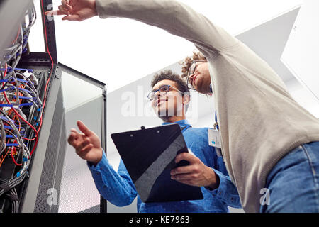 Männliche IT-Techniker mit Clipboard sprechen bei Panel in Server Zimmer Stockfoto