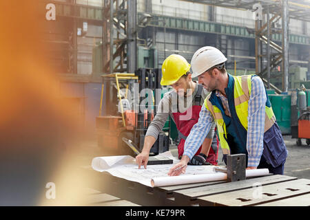 Männliche Ingenieure überprüfen Baupläne im Werk Stockfoto