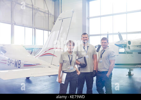 Portrait zuversichtlich, Mechaniker, Ingenieure im Hangar stehen Stockfoto