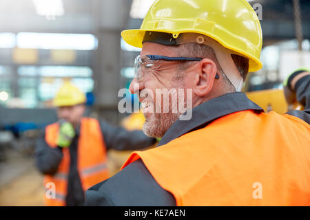 Profil lächelnder männlicher Arbeiter in der Fabrik Stockfoto