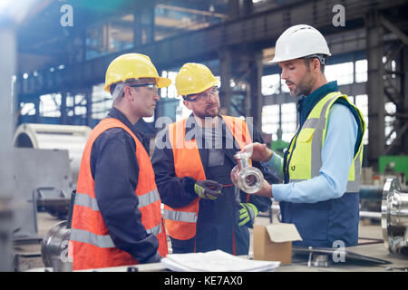 Männliche Ingenieure diskutieren Stahlteil im Werk Stockfoto