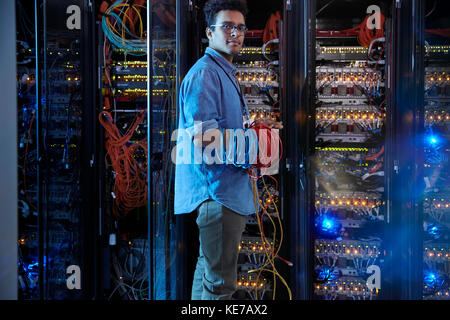 Portrait selbstbewusster IT-Techniker, der Kabel im Serverraum hält Stockfoto
