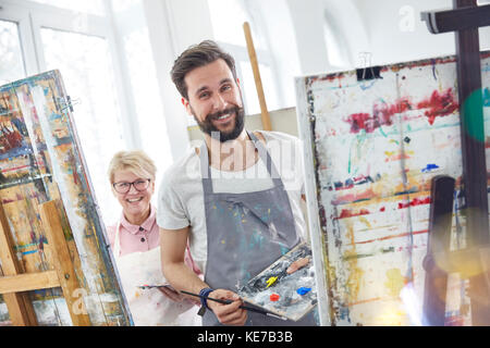 Portrait lächelnde Künstler Malerei an Staffeleien in Art Class Studio Stockfoto
