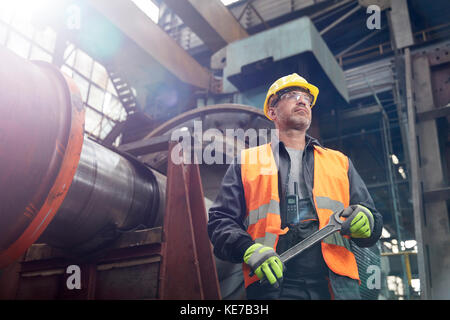 Selbstbewusster Arbeiter mit Schraubenschlüssel im Werk Stockfoto