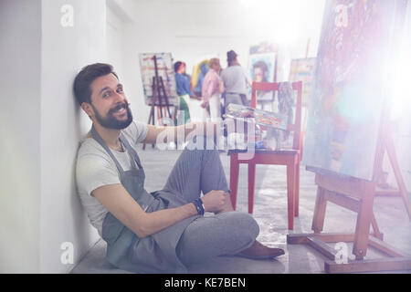 Portrait lächelnder männlicher Künstler mit Palettenmalerei an Staffelei Art Class Studio Stockfoto
