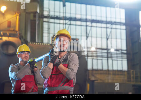 Männliche Arbeiter tragen Stahlteil in der Fabrik Stockfoto