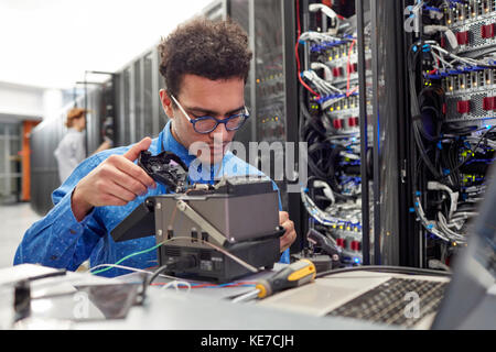 Männlicher IT-Techniker, der die Ausrüstung im Serverraum repariert Stockfoto