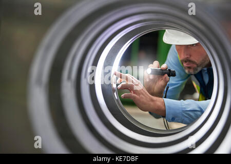 Männlicher Ingenieur mit Taschenlampe Inspektion Stahlzylinder Stockfoto