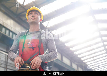 Männliche Arbeiter, die Maschinen mit Fernbedienung in der Fabrik bedienen Stockfoto