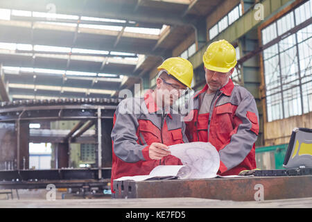 Männliche Ingenieure überprüfen Baupläne im Werk Stockfoto