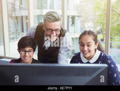 Männlicher Lehrer und Schüler, die am Computer in der Bibliothek forschen Stockfoto