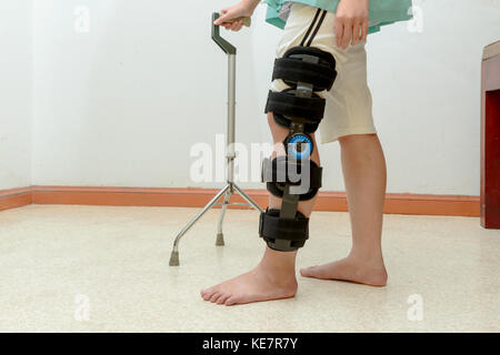 Frau Gehen auf Krücken, das Tragen von Knie Unterstützung im rehab Zentrum Stockfoto