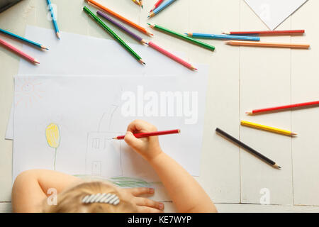 Das Mädchen zieht ihr Haus mit Buntstiften. Stockfoto