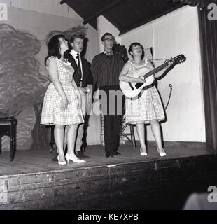 1960, historische, vier jungen erwachsenen männlichen und weiblichen Sänger mit Gitarre, auf der Bühne des Borough Assembley Hall, Aylesbury, Bucks, England. Stockfoto