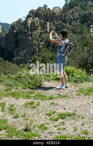 Junge Frau, die Fotos während einer Wanderung im Esterel-Massiv macht, einem Gebirgszug der Mittelmeerküste in den Departements Var und Alpes-Maritimes Stockfoto