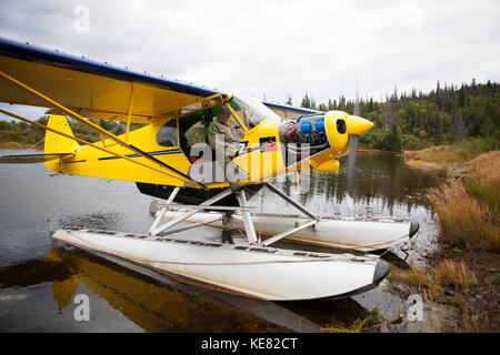 Pilot in einem Piper J-3 Super Cub Beach am Lake Iliamna, im Südwesten von Alaska, USA Stockfoto