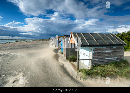 Hübsche Strandhütten unter einem dramatischen Himmel bei West Wittering auf der Sussex coast Stockfoto