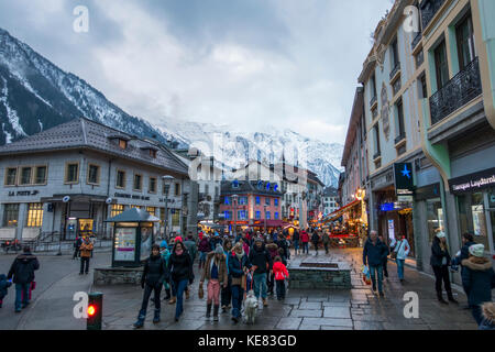 Touristen auf den Straßen neben Geschäften mit Blick auf die Bergkette, Chamonix, Frankreich Stockfoto