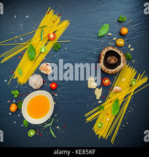 Italienisches Essen Konzept. Spaghetti mit Zutaten Basilikum, Tomate, Knoblauch, Pfeffer, Champignon, Zucchini und Parmesan auf dunklem Hintergrund fl Stockfoto