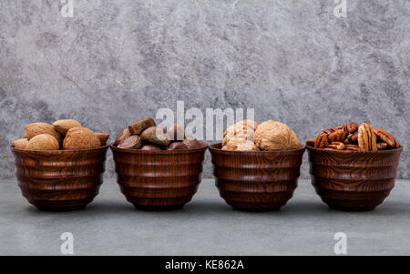 Ganze Mandeln, Walnüsse, ganze Haselnuss und Pekannuss in Houten setup mit Stein Hintergrund. selektive Fokus Tiefenschärfe. Stockfoto