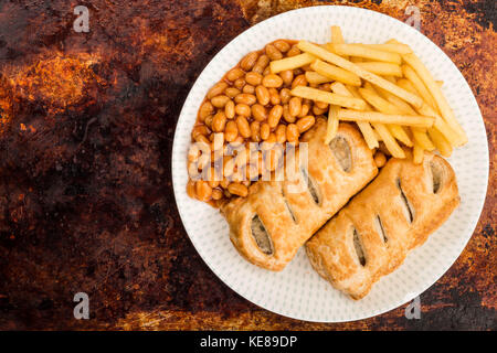 Würstchen, Brötchen mit Baked Beans Chips und Pommes frites auf einem distressed Backofen oder Backblech mit Kopie Raum Stockfoto