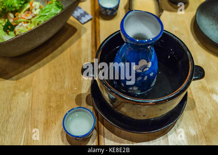 Japanische hot Sake in heißem Wasser Schüssel auf hölzernen Tisch Hintergrund Stockfoto