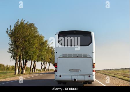 Weiß Intercity Bus ist eine Straße entlang fahren. Zurück anzeigen. sonnigen Tag. Der Himmel ohne Wolken. Stockfoto