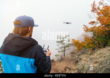 Junger Mann Handhabung Drone, mit Fernbedienung. Neue Technologien und Trends in der Foto- und Videoaufnahmen. Stockfoto