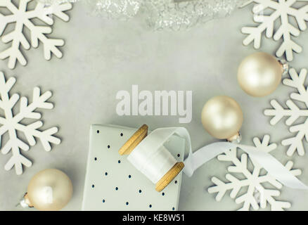 Geschenkboxen in Silber Papier gewickelt. Holz- Schieber mit Weiß gewellt Seidenband, Christbaumkugeln, Schneeflocken im Rahmen angeordnet. Kopieren Sie Platz für Text. Stockfoto