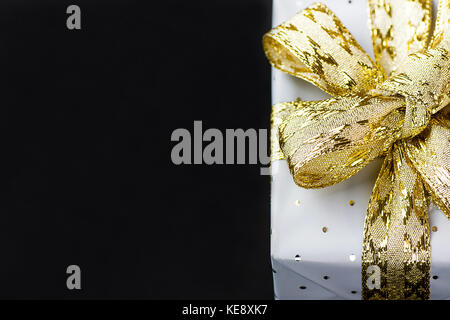 Elegante Geschenkbox in grauem Papier mit Polka Dots golden Band umwickelt. Weihnachten Silvester Valentinstag Geschenke shopping Verkauf. schwarzer Hintergrund Kopie spac Stockfoto