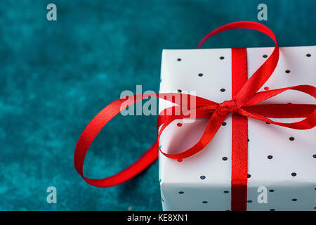 Elegante Geschenkbox in Grau Silber Papier mit Polka Dots red ribbon auf blauem Hintergrund gewickelt. Weihnachten neue Jahre präsentiert Shopping Verkauf. Kopieren Sie Platz Stockfoto