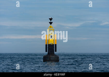 Der Rinne Stein Süden Kardinal marker Boje mit longships Leuchtturm im Hintergrund auf ein ruhiger Tag Stockfoto