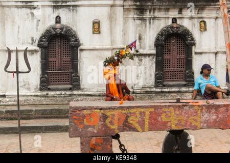 Noemie repetto/le pictorium - Nepal - kathmandu Pashupatinath Tempel. Welterbe seit 1979. - 20/09/2017 - Nepal/Kathmandu/Kathmandu - Nepal - Kathmandu. Der Tempel von Pashupatinath. Welterbe der Menschheit seit 1979. Ein Mann stellt Shiva in menschlicher Form und fährt auf den Standort des Tempels. Er trägt einen Kranz aus Blumen und den Körper in Orange im Einklang mit der Statue, Shiva, am Eingang zum Gelände gemalt. Stockfoto