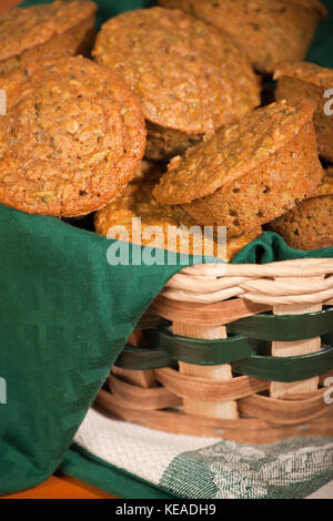 Zucchini Muffins in einem Tuch gestapelt - Weidenkorb gesäumt, ruht auf Kaffee Handtücher auf ein Holz Tisch Stockfoto