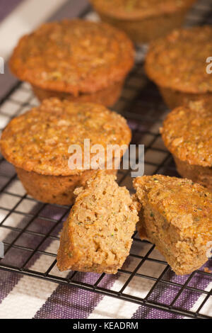 Frisch gebackene Zucchini muffins Kühlung in einem Draht Rack, mit einem Schnitt in der Hälfte Stockfoto