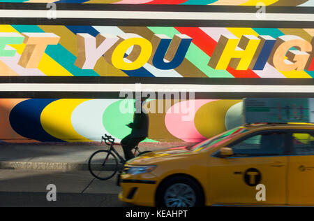 Mann auf dem Fahrrad und ein gelbes Taxi vorbei an New York City street art Stockfoto