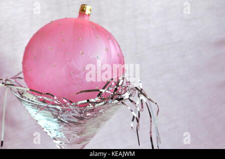 Frosted pink Christmas Ball Dekoration sitzen auf silbernen Haar in einem Schaft aus Glas mit Kopie Raum Stockfoto