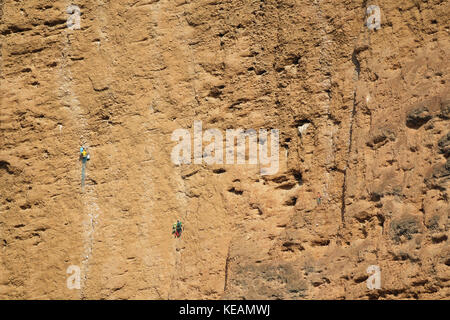 Gruppe der männlichen Bergsteiger von einem Felsen hängenden Stockfoto