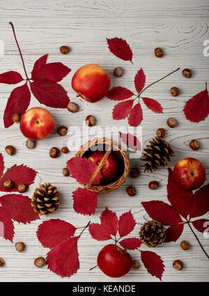Herbst rote Blätter mit Äpfeln auf einem hölzernen Hintergrund. Flachbild-Konzept legen. Stockfoto