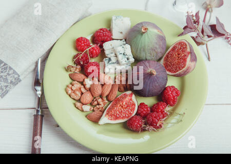 Mit der Tabelle, frische Feigen, Früchte, Beeren, Käse, Nüsse auf weißem Holz- Hintergrund Stockfoto
