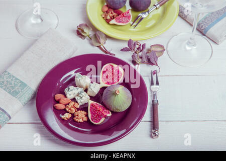 Mit der Tabelle, frische Feigen, Früchte, Beeren, Käse, Nüsse auf weißem Holz- Hintergrund Stockfoto
