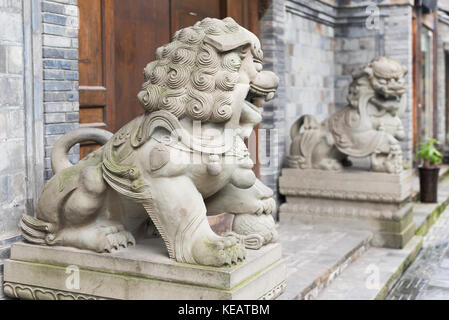 Zwei Löwen Stein Statuen vor einer Holztür in China Stockfoto