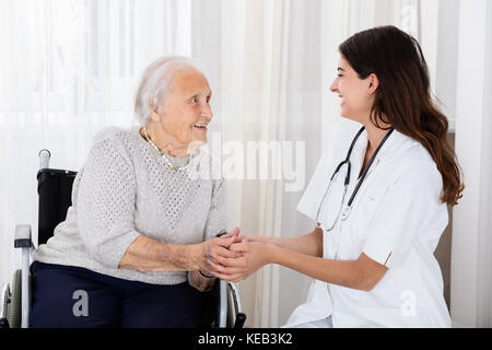 Gerne Ärztin trostreiche behinderte ältere Patient im Krankenhaus Stockfoto