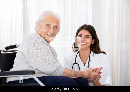 Portrait von Happy Ärztin mit behinderten älteren Patienten im Rollstuhl im Krankenhaus Stockfoto