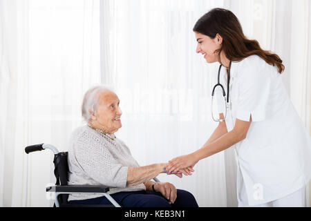 Ärztin trostreiche deaktiviert älterer Patienten im Rollstuhl im Krankenhaus Stockfoto